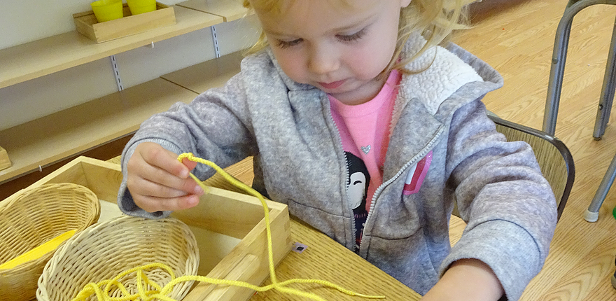 e63aae_cbe16fd009c7454cb567190ea94969a0 a child building coordination with Montessori threading activities
