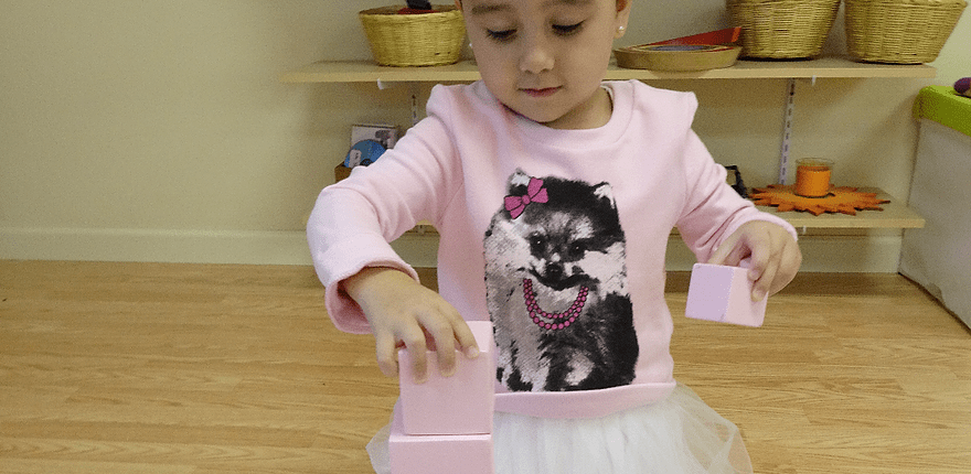 children exploring size relationships with Montessori knobbed cylinders