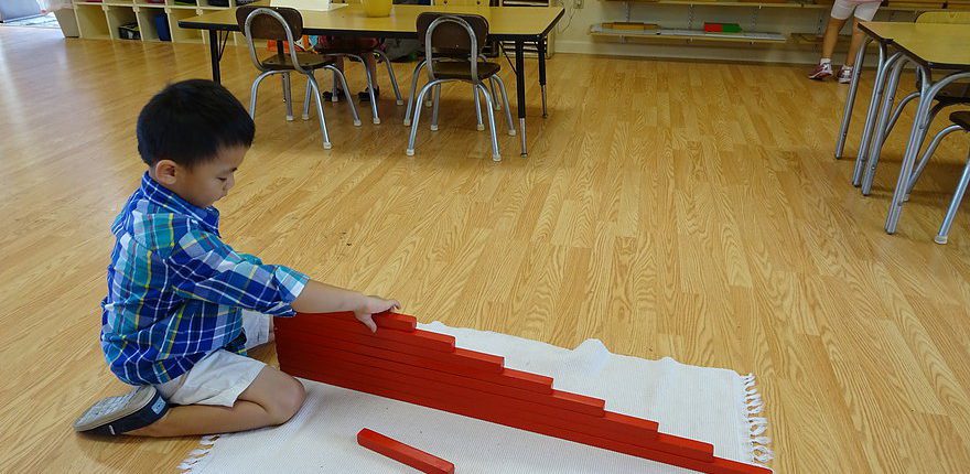 a child sequencing Montessori red rods to explore length and comparison