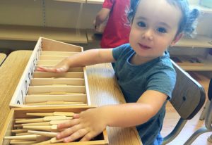 a child exploring size gradation with Montessori pink tower materials