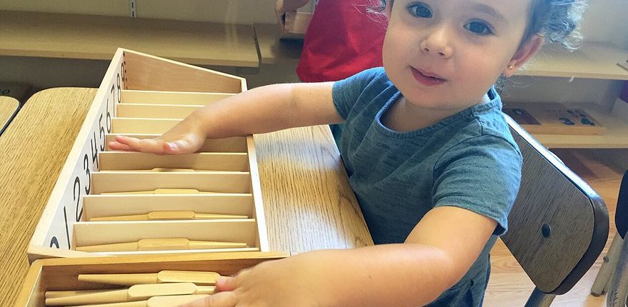 a child exploring size gradation with Montessori pink tower materials