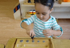 a child developing responsibility while cleaning up the Montessori classroom