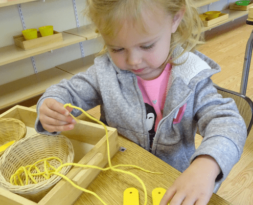 a child building coordination with Montessori threading activities