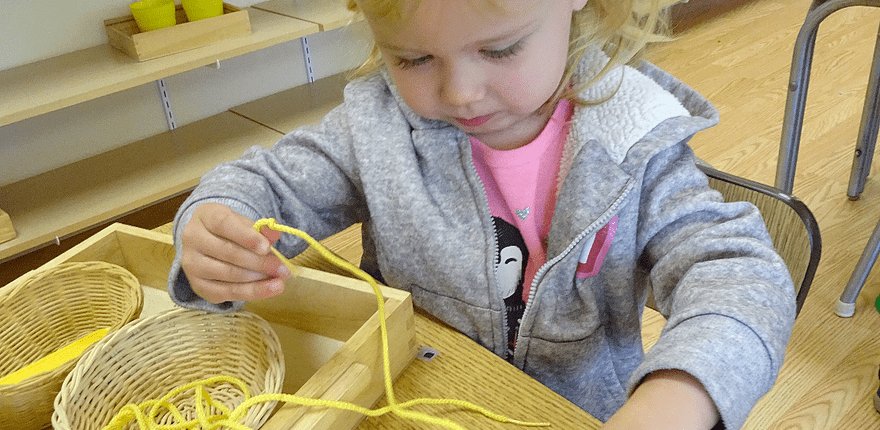 a child building coordination with Montessori threading activities