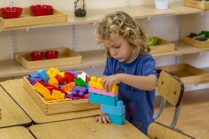 students practicing early writing skills with Montessori movable alphabet